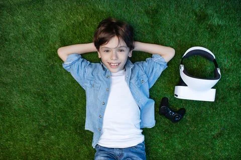 Happy Boy Lying on Grass with Virtual Reality Headset Stock Photos
