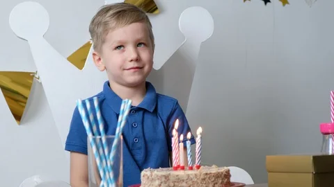 Happy boy making a wish celebrating birthday alone and blowing lighting candles Stock Footage 129324997