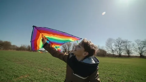 A happy boy is playing with a flying rainbow kite. Stock Footage 191972510