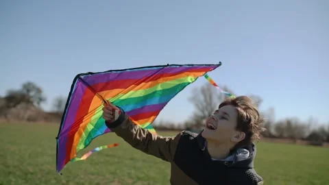 A happy boy is playing with a flying rainbow kite. Stock Footage 192943470