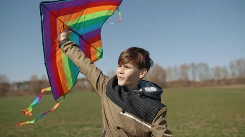 A happy boy is playing with a flying rainbow kite. Stock Footage 192943955