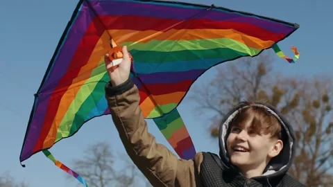 A happy boy is playing with a flying rainbow kite. Stock Footage 194311670