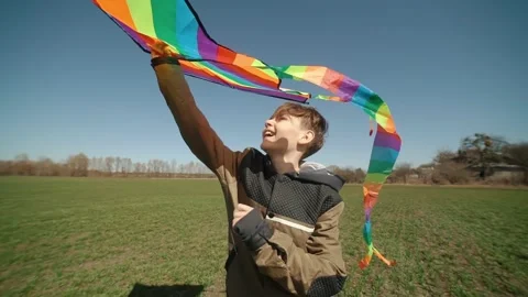 A happy boy is playing with a flying rainbow kite. Stock Footage 194311758