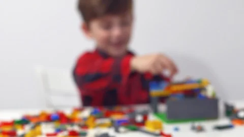 Happy boy playing a game of small plastic toy building blocks on a white table Stock Footage 91591737