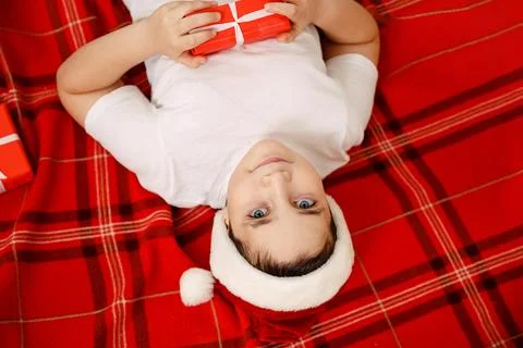 Happy boy playing with gift boxes in a cozy living room on Xmas eve. Fotos Stock