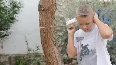 Happy boy playing, smiling, speaking and listening to a tin can phone Stock Footage 109160818