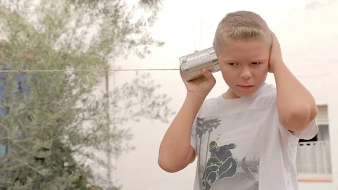 Happy boy playing, smiling, speaking and listening to a tin can phone Vidéo 109160824