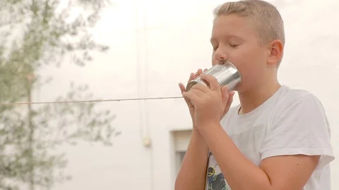 Happy boy playing, smiling, speaking and listening to a tin can phone Stock Footage 109160890