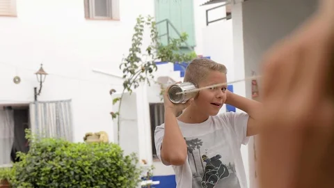 Happy boy playing, smiling, speaking and listening to a tin can phone Stock Footage 109160935
