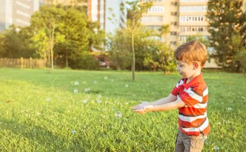 Happy boy playing with soap bubbles in the park Foto stock
