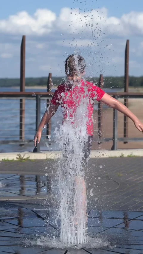 Happy boy playing with splash pad water fountain, sunny summer day, slow motion Stock Footage 341519189