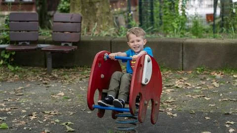Happy Boy Playing on Spring Rider at Playground in City Park Фото