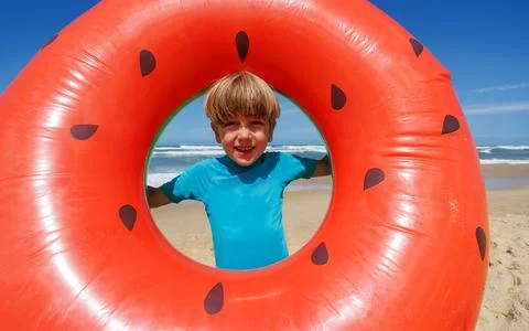 Happy boy playing with watermelon float at beach on sunny day Stock Photos