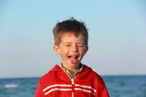 Happy boy in red jacket making faces with his eyes closed Stock Photos