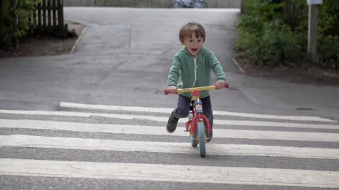 Happy Boy riding across the road on pedestrian crossing Stock Footage 113446779