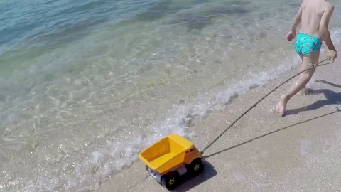 Happy Boy Running Along Beach with Toy Truck Stock Footage 83087397