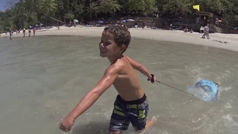 Happy boy running and jumping into the sea water. Slow motion Video stock 76849101