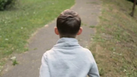 Happy boy running down the avenue in the park Stock Footage 76956236