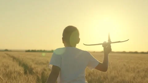 Happy boy runs with toy plane across field, flying into future. Kid aviator, Boy Video stock 242584331