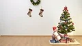 The happy boy sit on the floor and hold a gift near the christmas tree 4k or 4k+ Resolution