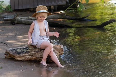 Happy boy sits by river Stock Photos