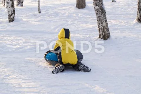 Happy boy slipped on the tubing from the mountain in winter Park. Stock Photos