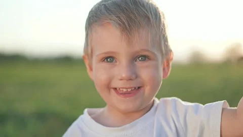Happy boy smiling in green meadow. Toddler laughing with wide eyes and joy Stock Footage 320114130