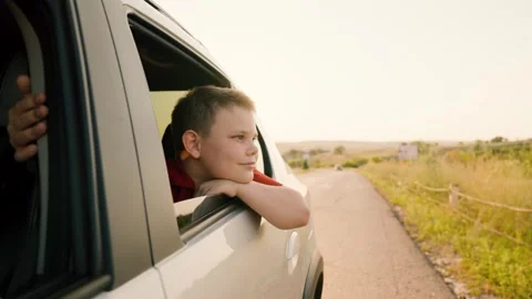 Happy boy son kid car window, asphalt road, catches sun glare with his fingers Stock Footage 263052481