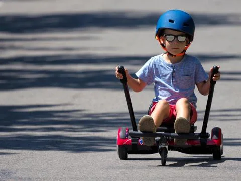 Happy boy standing on hoverboard or gyroscooter with kart accessory kit outdoor Stock Photos