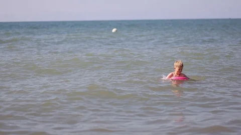Happy boy swims on an inflatable circle on the waves in the blue sea Stock Footage 117482486