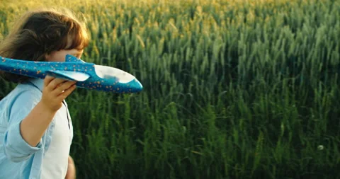 Happy boy throwing paper plane running in the field on sunny day. Child's play Stock Footage 205927168