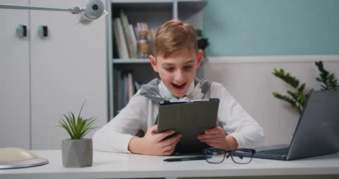 Happy boy using tablet sitting on table, smiling small kid watch online cartoons Stock Footage 232000052