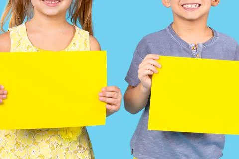 Happy boy in violet button t-shirt and girl in yellow floral dress holding two Stock-Fotos