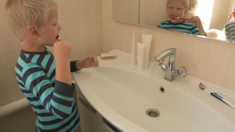 Happy boy washes his hands with soap and brushes his teeth in bathroom. Child Stock Footage 93534458