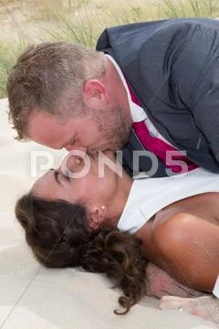 Happy bride and groom embracing lying on the wooden floor Stock Photos