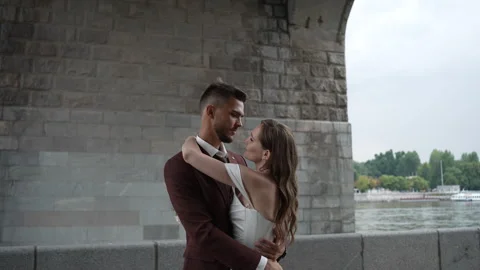 Happy bride and groom posing in formal wear in front of bridge, having fun Vidéo 267876985