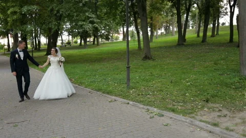 Happy bride and groom walking in park. Stock Footage 85594329