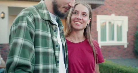 Happy brunette guy with a beard in a checkered shirt hugs his blonde girlfriend Stock Footage 283832479