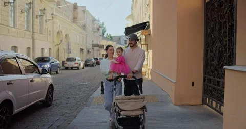 Happy brunette guy in a cap in a white shirt walks with his wife and little Video stock 285698731