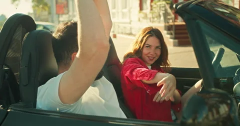 Happy brunette guy dancing with his girlfriend in a red shirt Sitting in a black Stock Footage 280575893