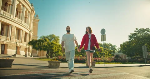 Happy brunette guy in a white T-shirt holds the hand of his girlfriend in a red Stock Footage 280578608