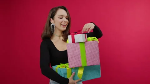 A happy brunette holds three boxes of gifts on a red background Stock Footage 293166025