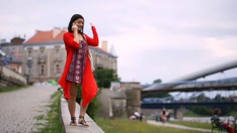 Happy brunette walking on the path next to the river and chatting on cellphone Stock Footage 82261217