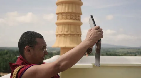 Happy Buddhist Monk taking selfie with tablet from top of monastery Stock Footage 60052820