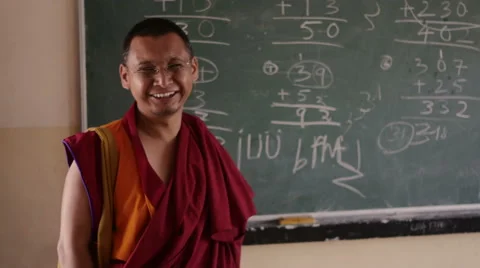 Happy Buddhist Monk teacher in front of clackboard Stock Footage 60175672