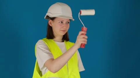 Happy builder in helmet uses soft roller brush on blue Stock Footage 273495273