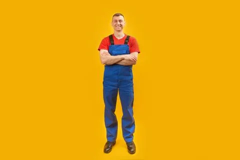 Happy builder workman crossing hands posing on yellow studio background. Copy Stock-Fotos