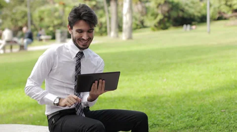 Happy business young man using tablet PC outside on a park Stock Footage 32360044