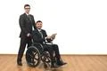 The happy businessman and an invalid hold a tablet on the white wall backgrou Photo