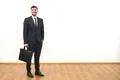 The happy businessman with a briefcase standing on the white wall background Photo